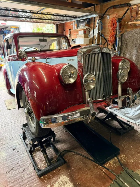 Two-tone classic saloon up on ramps in a garage for servicing