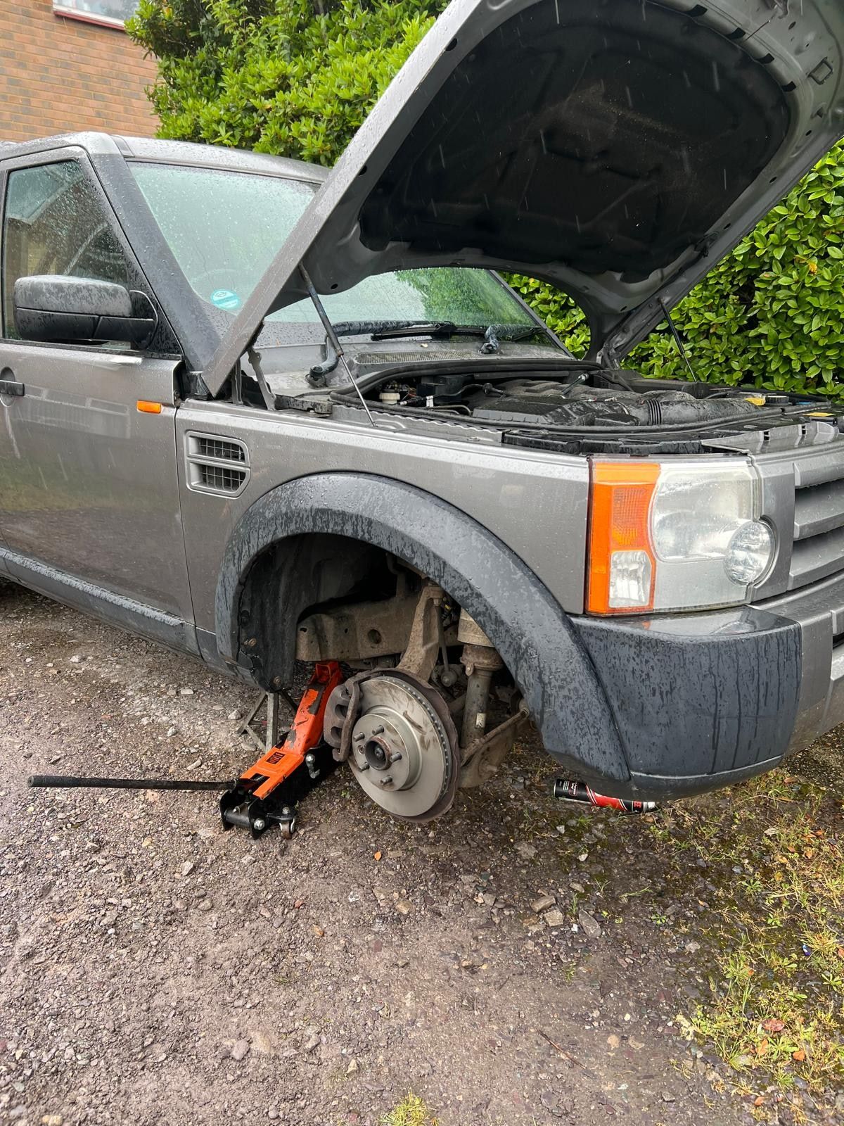 Land Rover Discovery jacked up with the front wheel off and bonnet raised, repaired where it stood